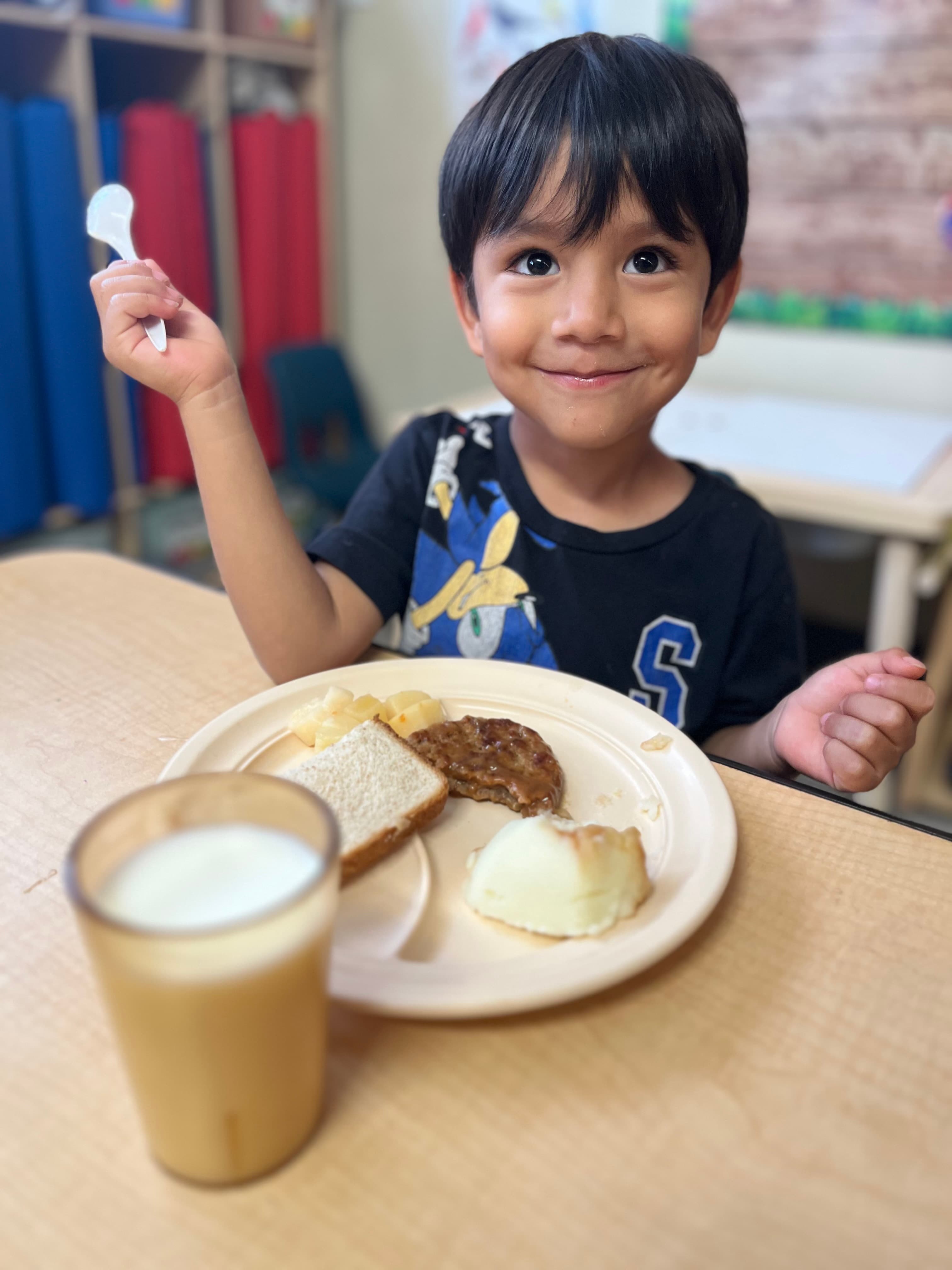 Boy smiling with his lunch plate at ABQ Childcare